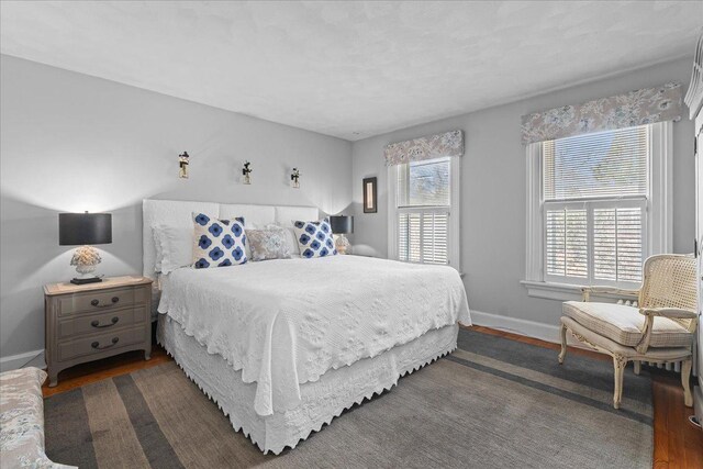 bedroom with dark wood finished floors and baseboards