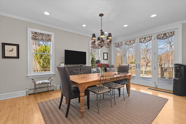 dining space with an inviting chandelier, ornamental molding, a baseboard heating unit, baseboards, and light wood-style flooring
