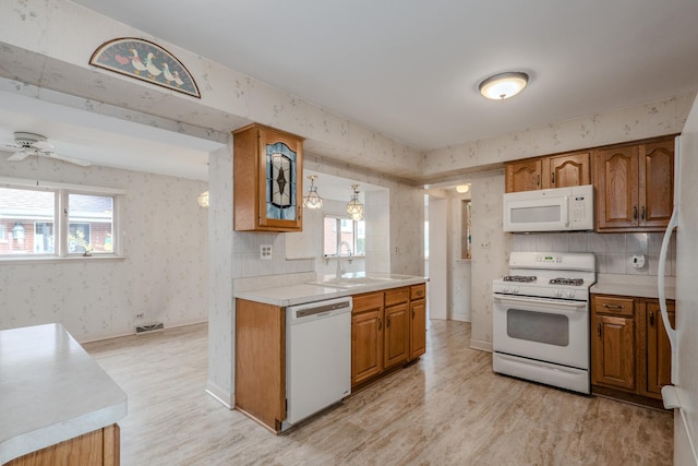 kitchen featuring brown cabinets, a sink, white appliances, and light countertops