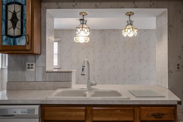 kitchen with white dishwasher, wallpapered walls, brown cabinets, and a sink