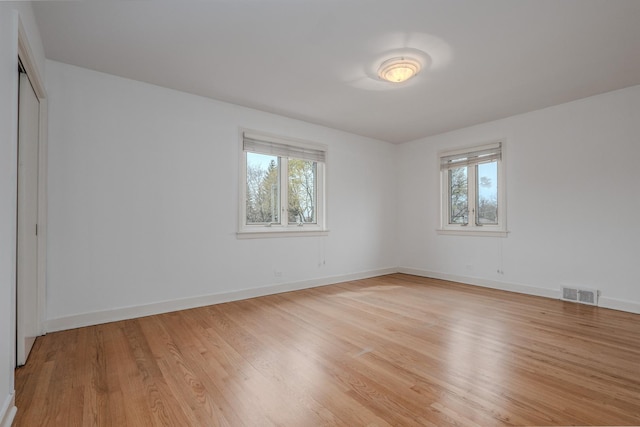 unfurnished bedroom featuring multiple windows, visible vents, and light wood-style flooring