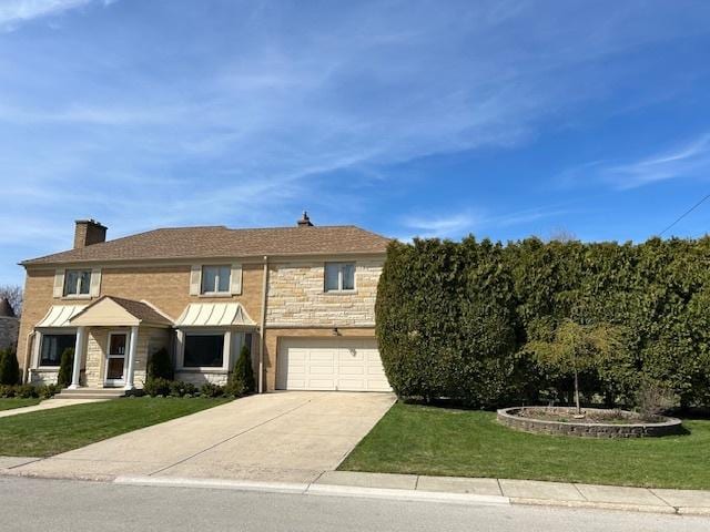 view of front of home featuring a front lawn, driveway, stone siding, and an attached garage