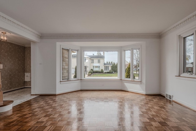 unfurnished room with wallpapered walls, visible vents, baseboards, and ornamental molding
