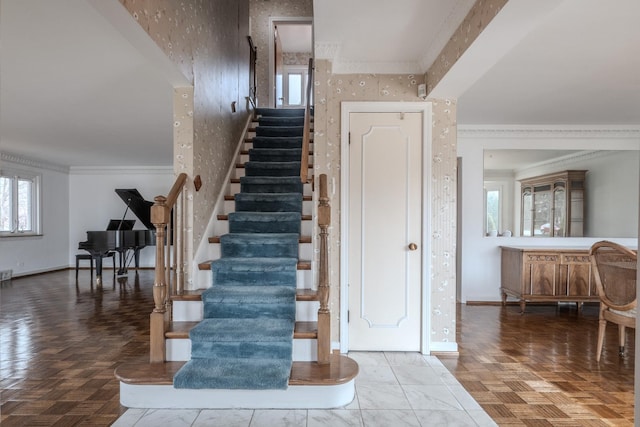 staircase with ornamental molding, wallpapered walls, baseboards, and plenty of natural light