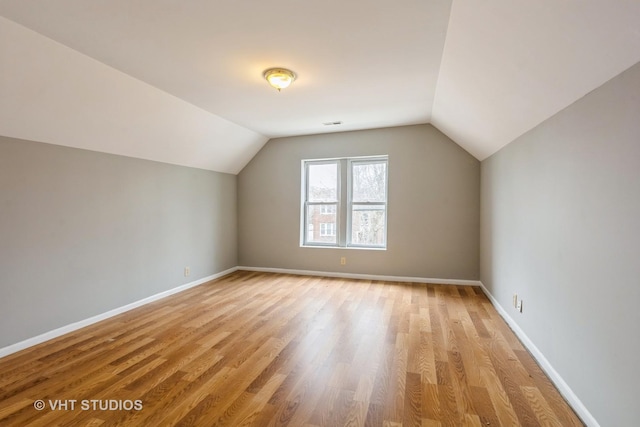 additional living space featuring baseboards, light wood-style floors, and lofted ceiling