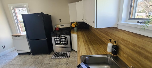 kitchen featuring stainless steel gas stove, freestanding refrigerator, white cabinets, dark countertops, and white dishwasher