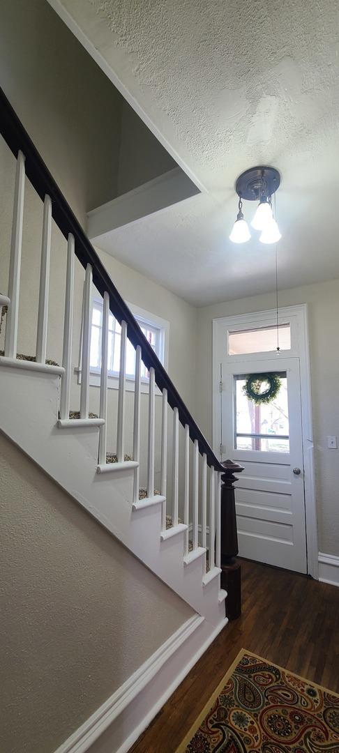 stairway with a textured ceiling, baseboards, and wood finished floors