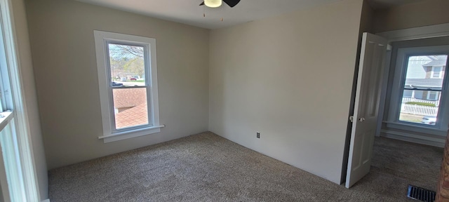 spare room with carpet flooring, a ceiling fan, and visible vents
