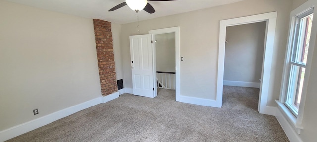 unfurnished bedroom with baseboards, multiple windows, carpet flooring, and a ceiling fan