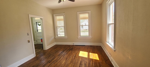 empty room with dark wood-type flooring, baseboards, a ceiling fan, and visible vents