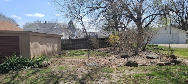 view of yard with an outbuilding, a garage, and fence