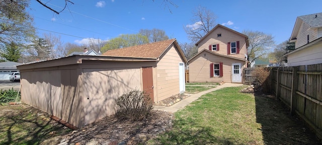 rear view of house featuring an outdoor structure, fence, and a lawn