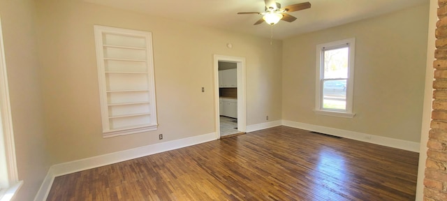 empty room with visible vents, built in features, baseboards, ceiling fan, and dark wood finished floors