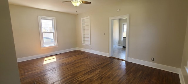 empty room with built in features, dark wood-style flooring, baseboards, and a ceiling fan