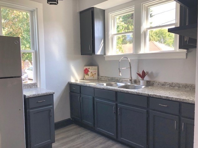 1639 Victoria Ave, North Chicago, IL 60064 - kitchen with light wood-style floors, freestanding refrigerator, light countertops, a sink, and baseboards