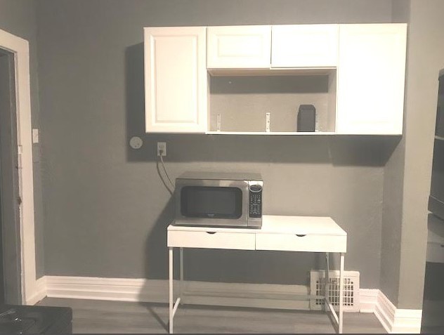 1639 Victoria Ave, North Chicago, IL 60064 - room details with stainless steel microwave, white cabinets, baseboards, and open shelves