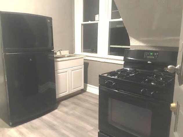 1639 Victoria Ave, North Chicago, IL 60064 - kitchen with baseboards, light wood-style floors, a sink, and black appliances