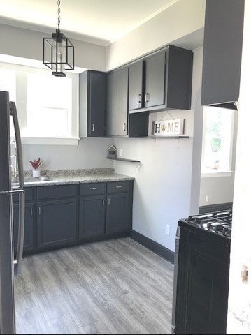 1639 Victoria Ave, North Chicago, IL 60064 - kitchen with light wood-style floors, pendant lighting, black appliances, and a healthy amount of sunlight