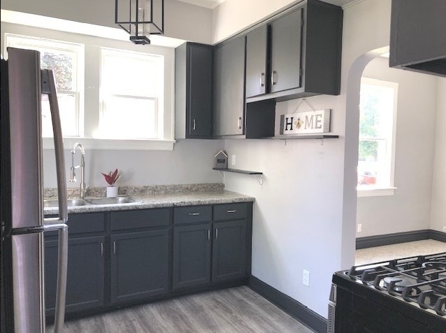 1639 Victoria Ave, North Chicago, IL 60064 - kitchen with arched walkways, a sink, light countertops, freestanding refrigerator, and light wood-style floors