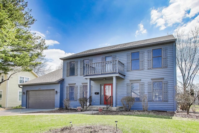 colonial home with a garage, driveway, a front lawn, and a balcony