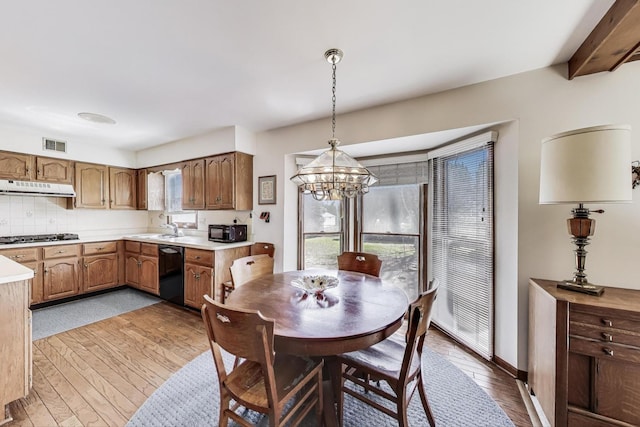 dining area featuring a notable chandelier, light wood-style flooring, and visible vents