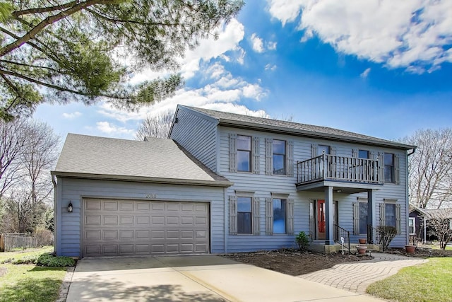 colonial inspired home featuring a garage, fence, driveway, and a balcony