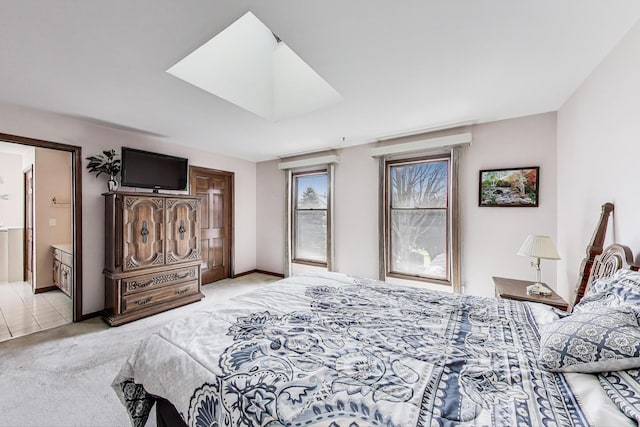 bedroom with baseboards, ensuite bathroom, and light colored carpet