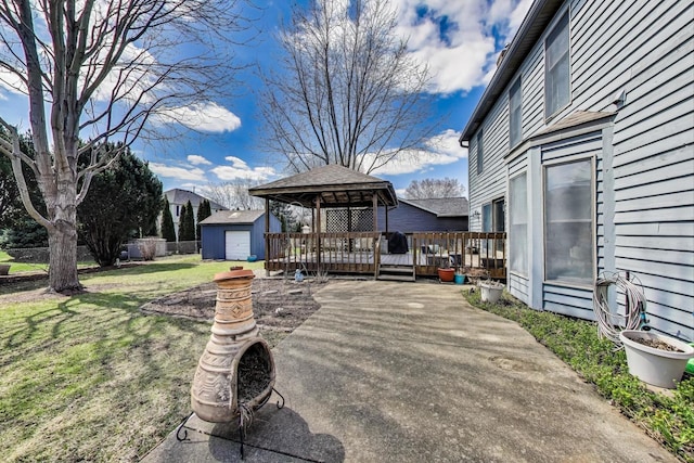 view of patio with a gazebo, a wooden deck, and an outbuilding