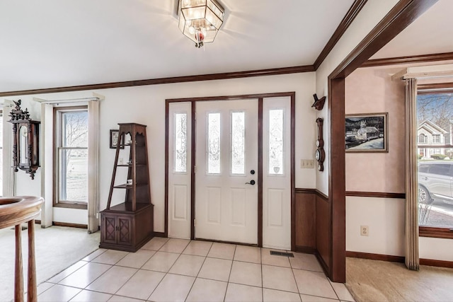 entrance foyer featuring crown molding, baseboards, light colored carpet, and a wealth of natural light