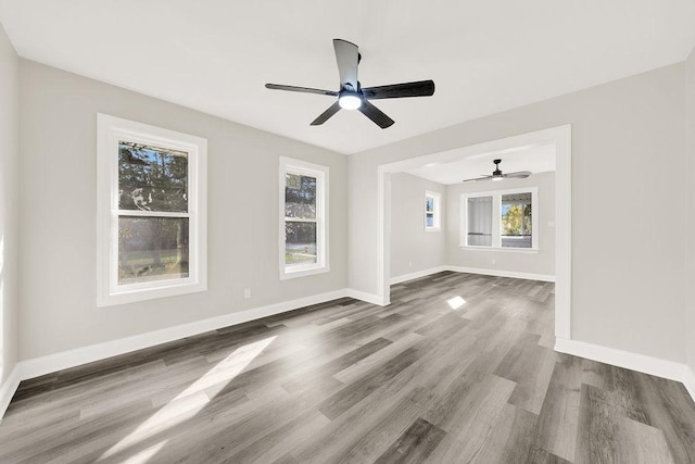 unfurnished room with baseboards, wood finished floors, and a healthy amount of sunlight