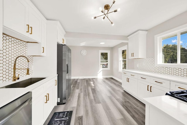 kitchen with a sink, light countertops, appliances with stainless steel finishes, and a chandelier