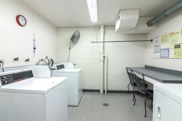 common laundry area with independent washer and dryer, concrete block wall, and light floors