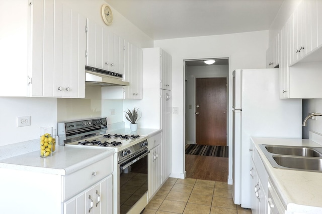 kitchen featuring white appliances, light tile patterned floors, light countertops, under cabinet range hood, and a sink