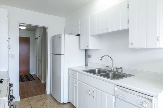 kitchen featuring white cabinets, white appliances, light countertops, and a sink