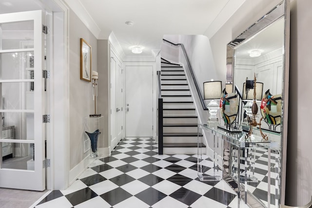 foyer entrance featuring tile patterned floors, baseboards, ornamental molding, and stairway