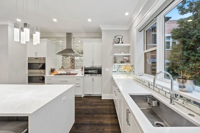 kitchen featuring wall chimney range hood, open shelves, a sink, stainless steel appliances, and decorative backsplash