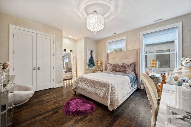 bedroom with baseboards, dark wood-style flooring, visible vents, and an inviting chandelier
