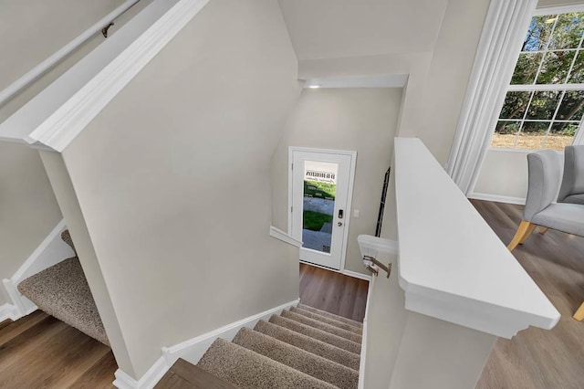 stairs featuring a wealth of natural light, lofted ceiling, baseboards, and wood finished floors