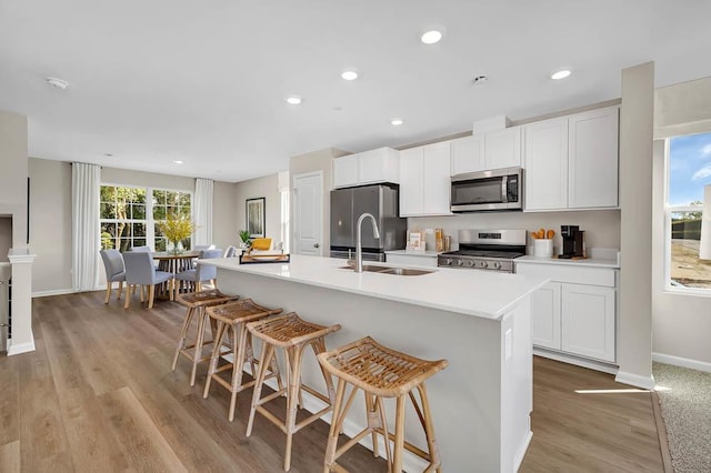 kitchen featuring a kitchen island with sink, a kitchen breakfast bar, white cabinetry, and appliances with stainless steel finishes