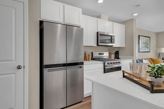 kitchen featuring white cabinets, light wood-style floors, recessed lighting, light stone countertops, and stainless steel appliances