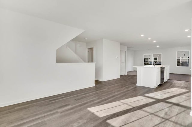 unfurnished living room featuring a sink, baseboards, recessed lighting, and dark wood finished floors