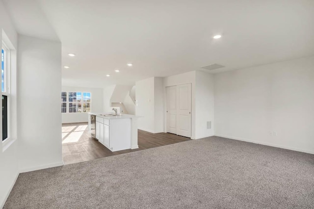 unfurnished living room with baseboards, recessed lighting, a sink, and dark carpet