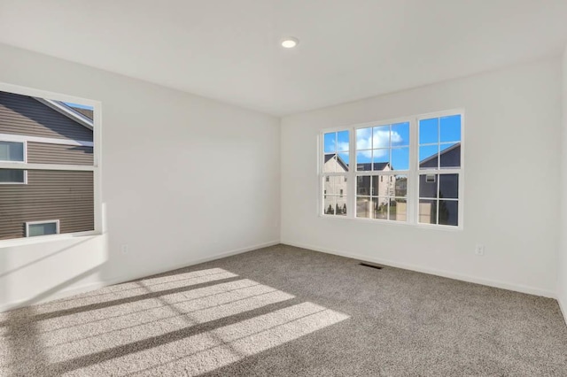 carpeted empty room featuring recessed lighting, visible vents, and baseboards