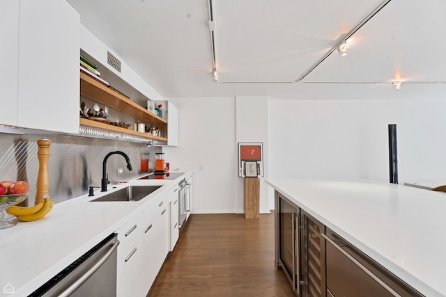 kitchen with a sink, light countertops, white cabinetry, stainless steel dishwasher, and rail lighting