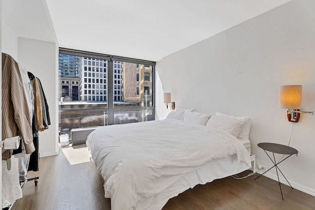 bedroom with baseboards, wood finished floors, and expansive windows