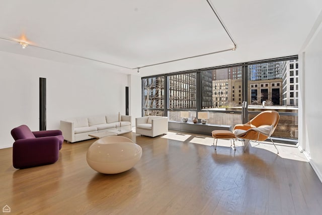 living area with rail lighting, a city view, and wood finished floors