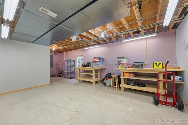 unfinished below grade area featuring baseboards, visible vents, and a workshop area