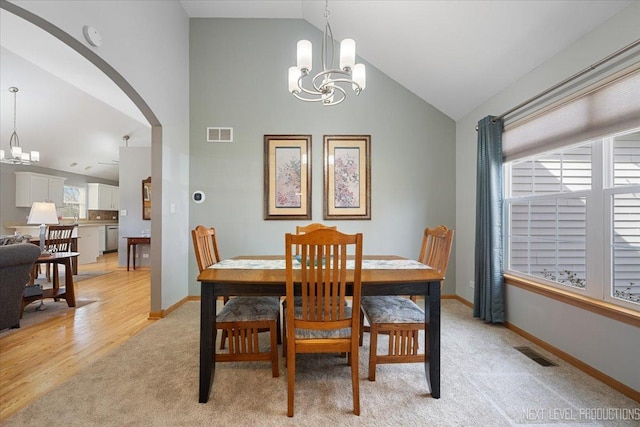 dining area featuring a chandelier, arched walkways, visible vents, and light carpet