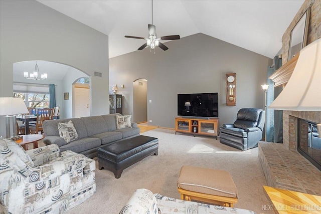 carpeted living room with high vaulted ceiling, ceiling fan with notable chandelier, arched walkways, a brick fireplace, and visible vents