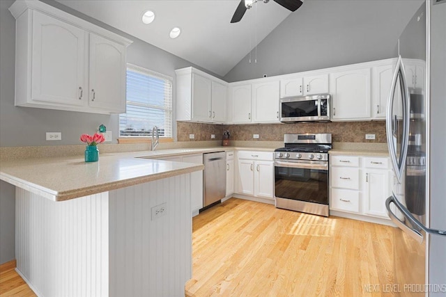 kitchen with vaulted ceiling, a ceiling fan, tasteful backsplash, a peninsula, and appliances with stainless steel finishes